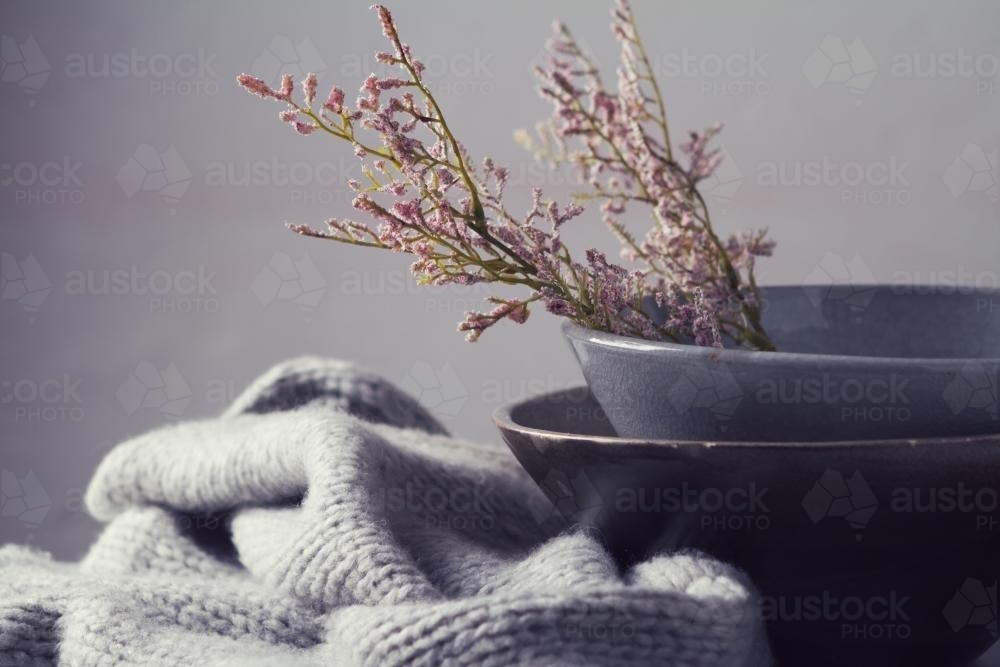 Winter still life flowers grey bowls and knitted scarf horizontal - Australian Stock Image