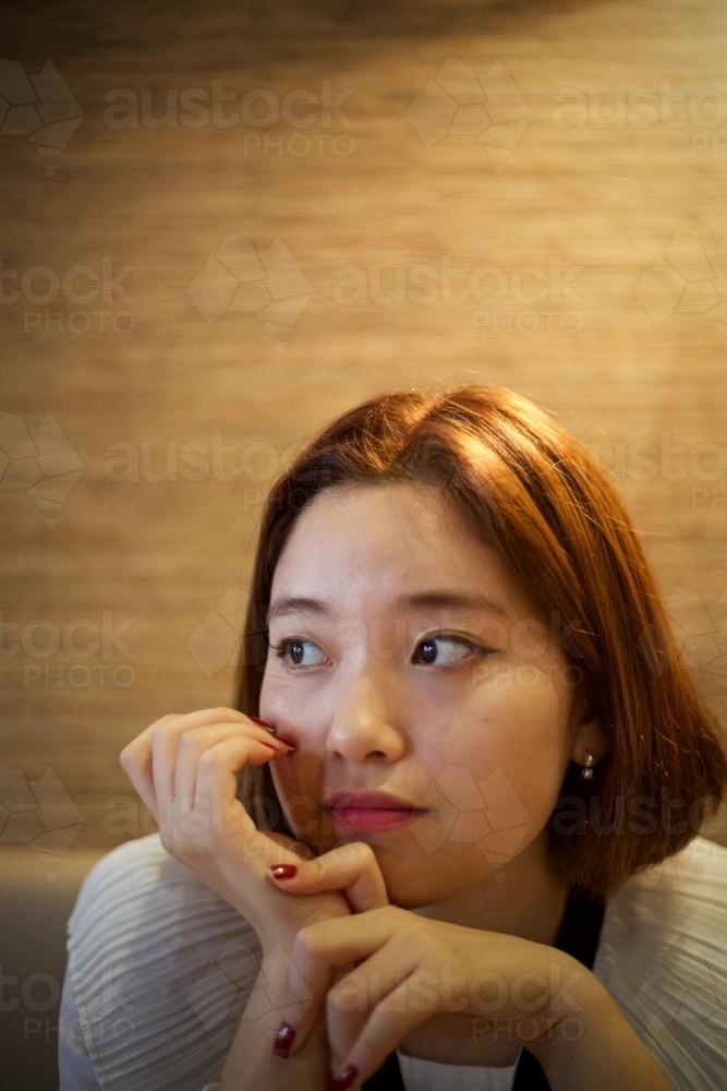 Woman sitting, looking away from camera - Australian Stock Image