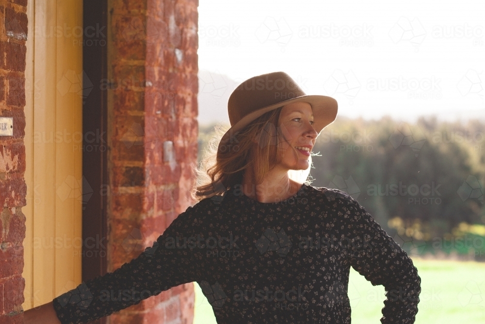 Woman smiling on the porch of a house in the country - Australian Stock Image