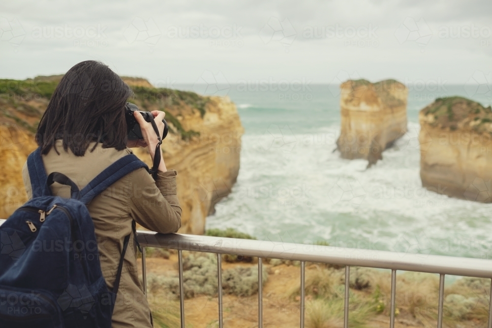 Woman taking picture of ocean and rock - Australian Stock Image