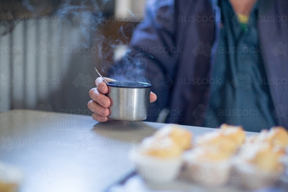Worker holding tea in a thermos cup - Australian Stock Image
