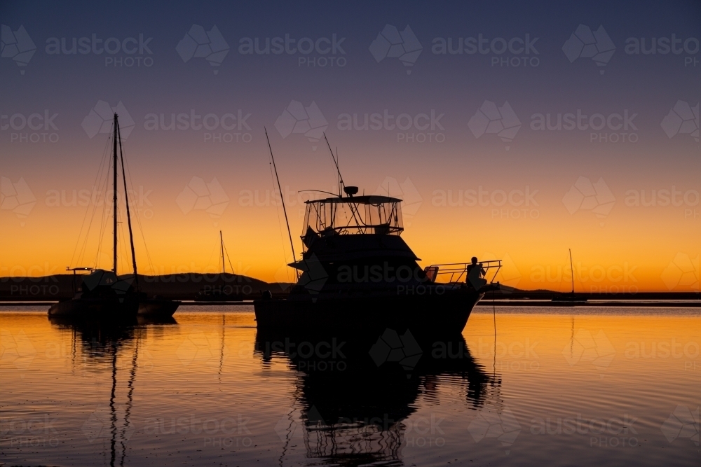Yacht reflections and silhouettes during sunset at the Town of 1770, Queensland. - Australian Stock Image