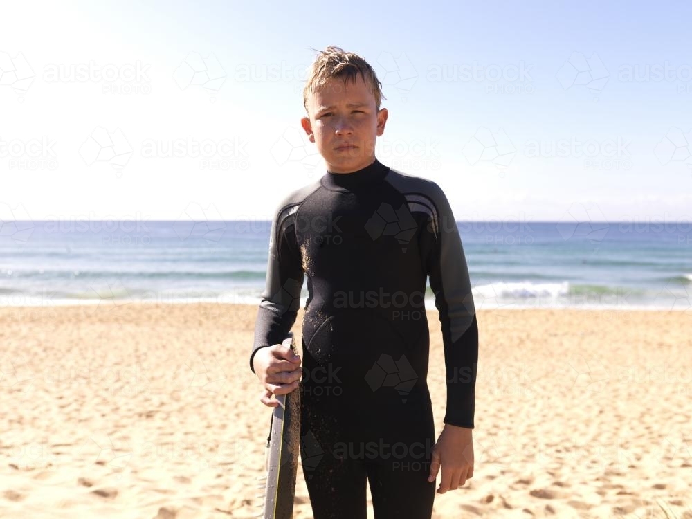 Young boy on beach in wetsuit after body boarding - Australian Stock Image