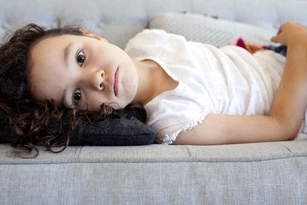 Young girl lying on sofa - Australian Stock Image