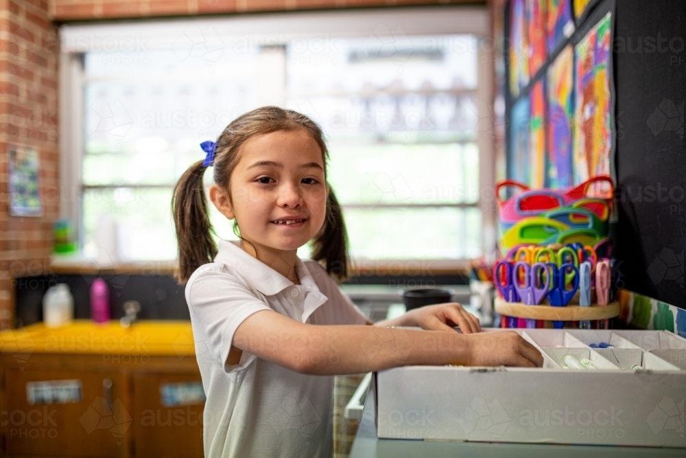Young schoolgirl in classroom smiling at camera - Australian Stock Image