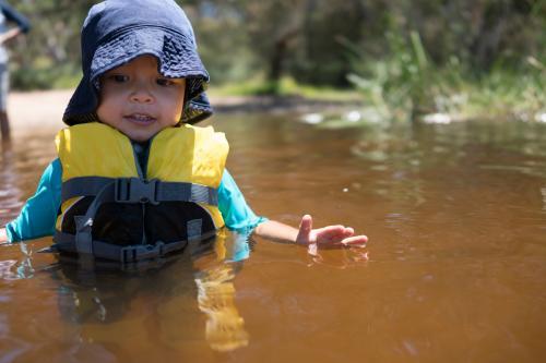 3 year old mixed race boy swims and plays in a river