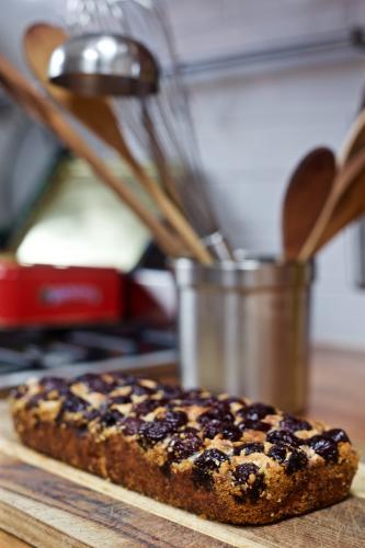 A baked cherry cake with kitchen utensils in the background