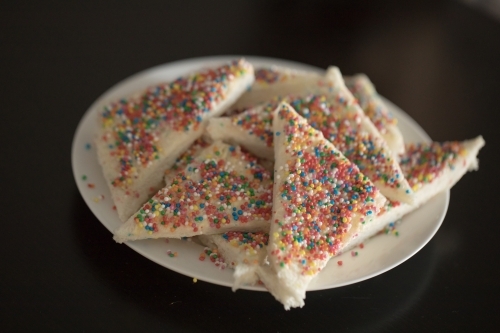 a Close up plate of fairy bread, bread buttered and then sprinkled with sprinkles