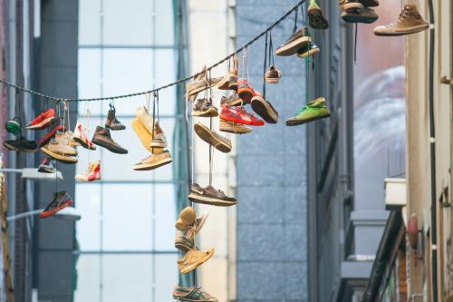 A collection of footwear hanging in a city laneway