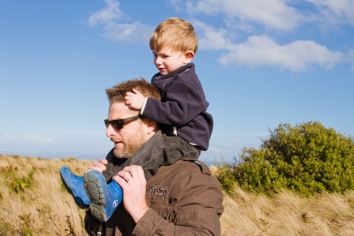 A father carrying a small boy on his shoulders outdoors
