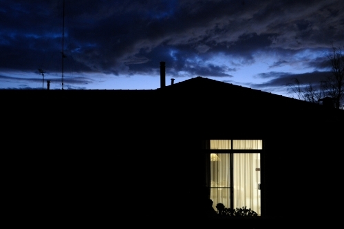 A house at night with a light on in one room