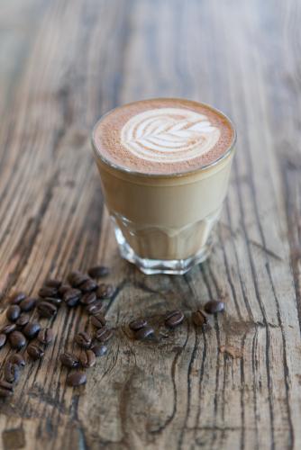 A latte on a wooden table with coffee beans