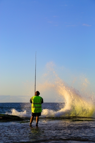 A man in his forties rock fishing at Wombarra Headland on the Illawarra Coast, NSW