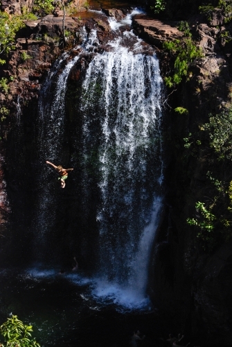 A man in mid air after jumping off a very high waterfall