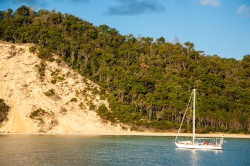 A sailing boat anchored in the water beside Moreton Island.