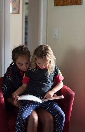 Aboriginal sisters reading a book together.
