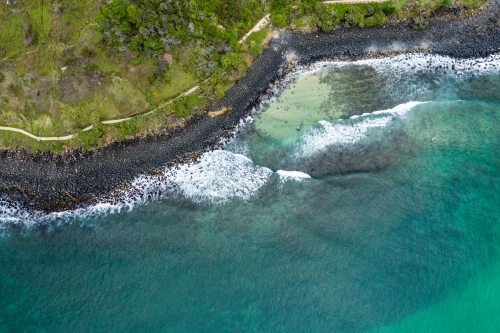 Aerial image of rocky coastline and beach front walking track