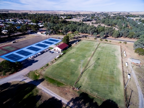Aerial shot of tennis complex with lawn and blue courts