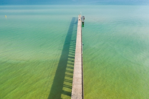 Aerial view of a long narrow jetty out over a calm bay