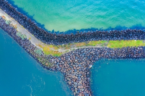 Aerial view of a rocky breakwater surrounded deep blue water