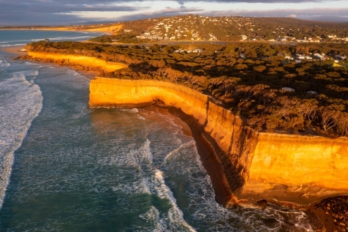 Aerial view of high coastal cliffs catching golden dawn side lighting