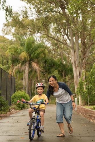 Asian mum teaching her mixed race boy to ride a bike