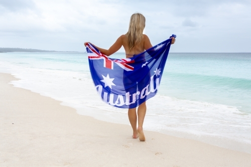 Australian woman walking along a beach waves washing up to her feet
