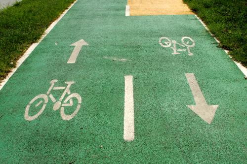 Bicycle and arrow signs painted in white on green asphalt