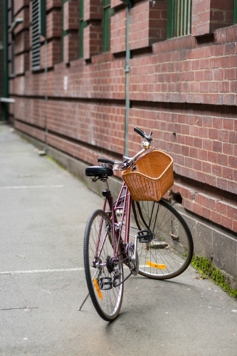 Bicycle with a woven basket parked next to a brick wall