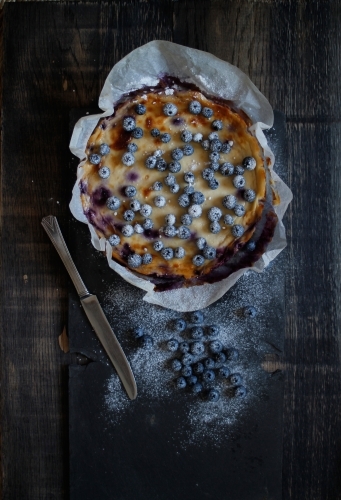 Blueberry cheesecake in baking paper on black background