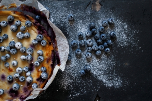 Blueberry cheesecake in baking paper on dark background