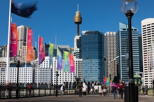 Blurred pedestrians walking across Pyrmont bridge with Sydney skyline background
