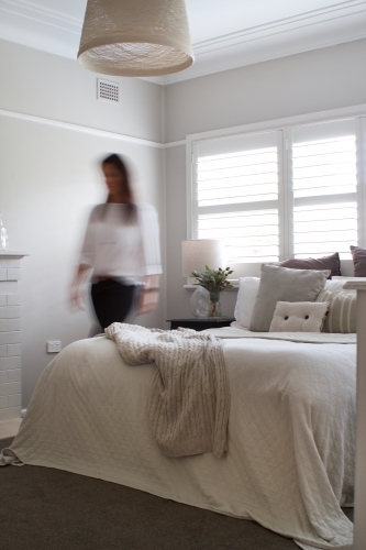 Blurred woman walking in bedroom with sunlit window