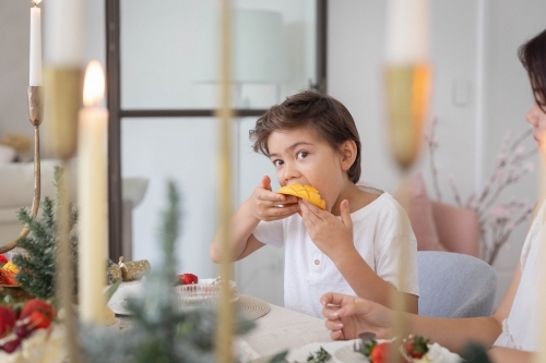 Boy eating slice of mango at christmas table