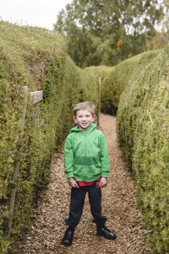 Boy standing in a maze smiling