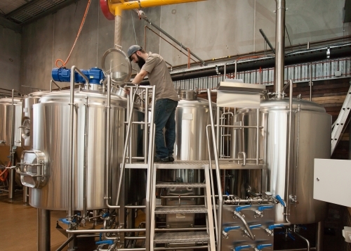 Brewer supervising mashing process in stainless steel tank