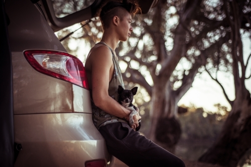 Camping life - woman sitting agains boot of car in the bush