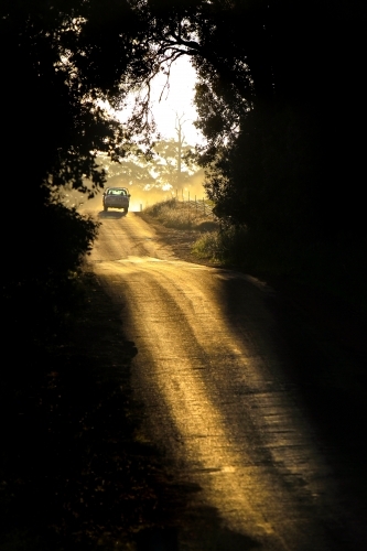 Car driving down country road at sunset