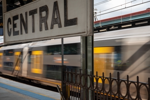 Central railway station sign with train passing the platform
