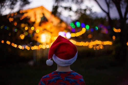 child wearing a santa hat looking at a christmas light display