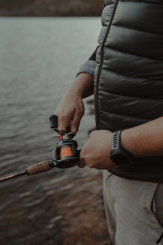 Close up detail shot of hands adjusting a reel while fishing
