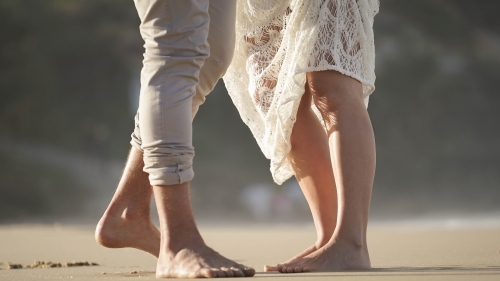 Close up of couples feet walking on beach
