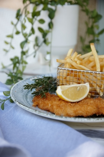 Close up of fish and chips with lemon slice on plate