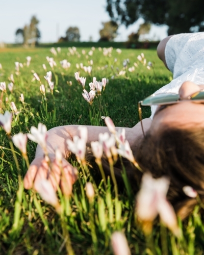 Close up of young girl lying on her back in a field of flowers