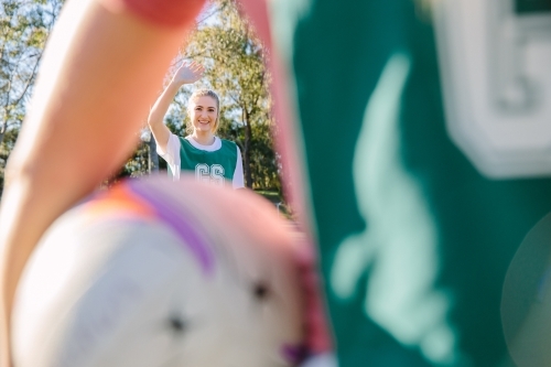 close up shot of a young woman framed in a blurry arm and net ball in the foreground