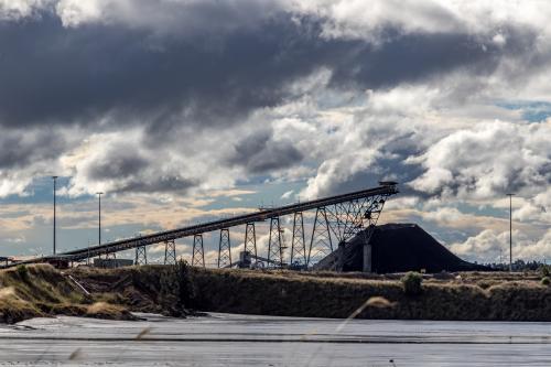 Coal conveyor and stockpile in the distance against dark clouds