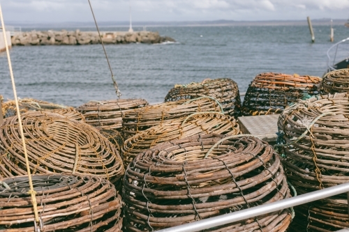 Crayfish pots on a commercial fishing boat at a wharf beside ocean