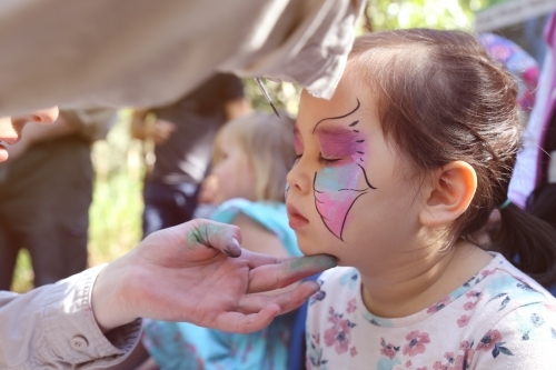 Cute girl getting face painted as a butterfly