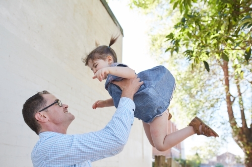 Dad playfully throwing daughter in the air