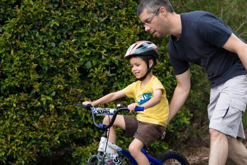 Dad teaching his son to ride a bike